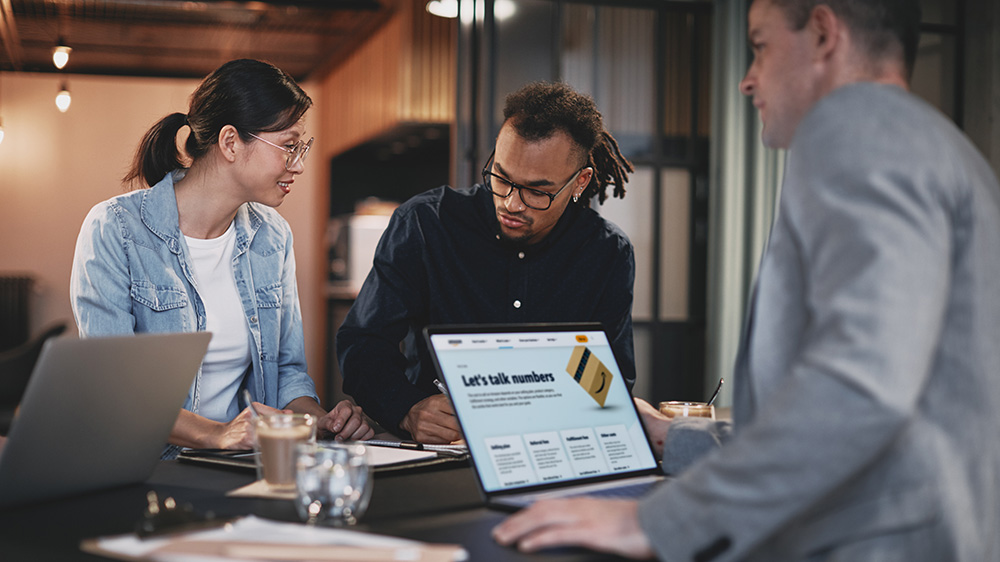two men and a woman looking at computers and discussing selling on Amazon